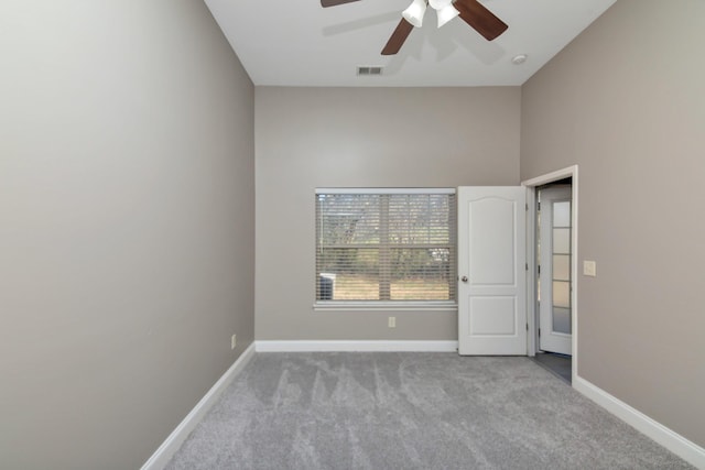 carpeted empty room with baseboards, visible vents, and ceiling fan