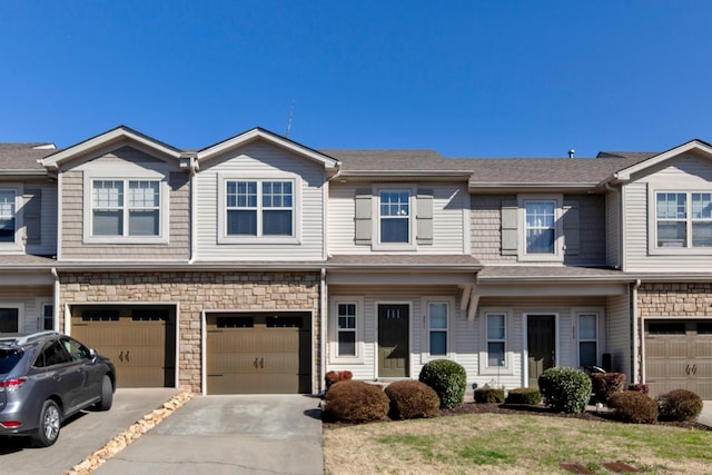 view of property featuring a garage, stone siding, driveway, and a shingled roof