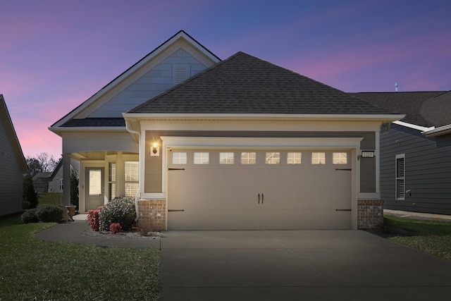 craftsman-style house featuring brick siding, a garage, driveway, and roof with shingles