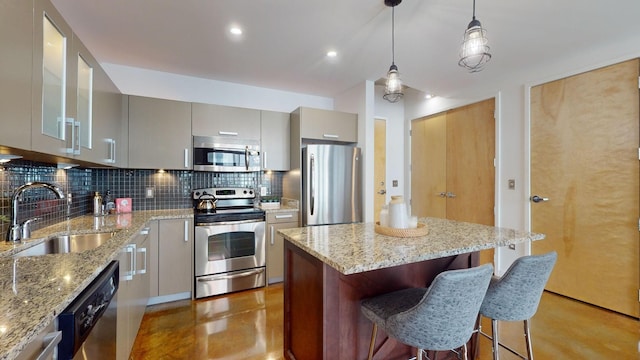 kitchen featuring gray cabinets, a sink, a kitchen island, appliances with stainless steel finishes, and decorative backsplash