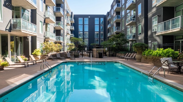 community pool with a patio area and fence