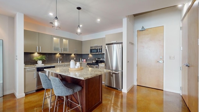 kitchen featuring a kitchen bar, gray cabinetry, a sink, tasteful backsplash, and stainless steel appliances