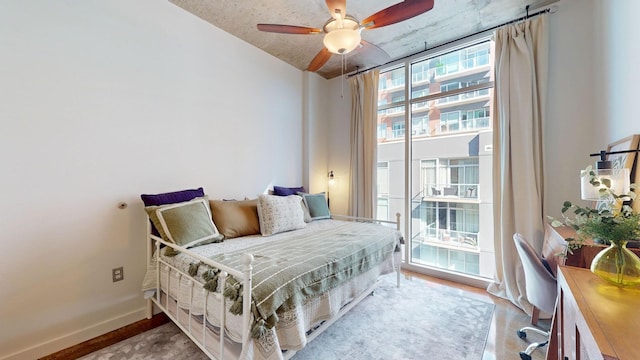 bedroom featuring baseboards, a ceiling fan, access to exterior, and floor to ceiling windows