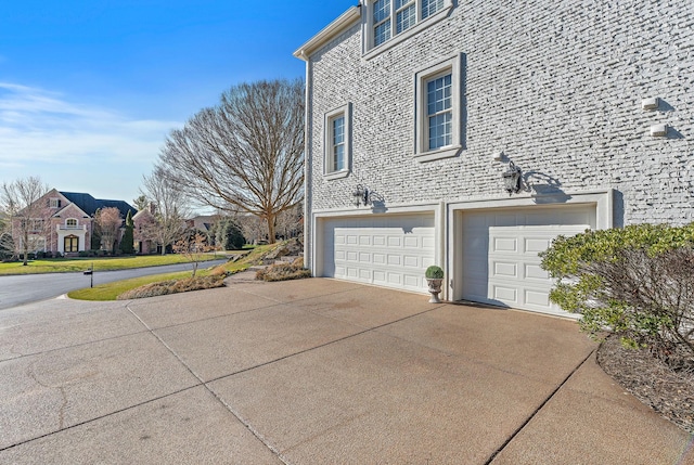 view of side of property featuring concrete driveway and a garage