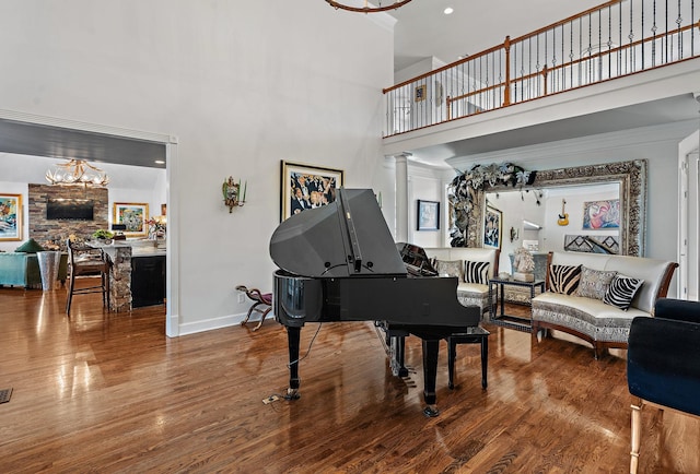 sitting room with a high ceiling, decorative columns, wood finished floors, and baseboards