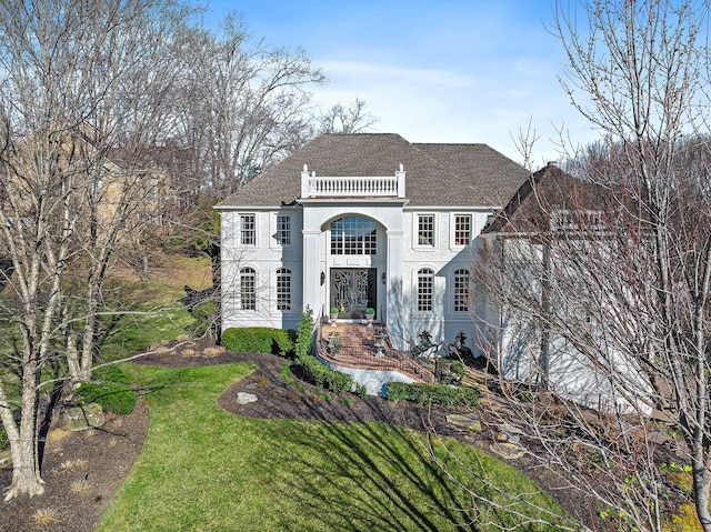 view of front of property with stucco siding, a front yard, and a balcony