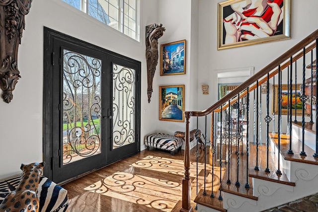 entrance foyer featuring stairway, french doors, a towering ceiling, and wood finished floors