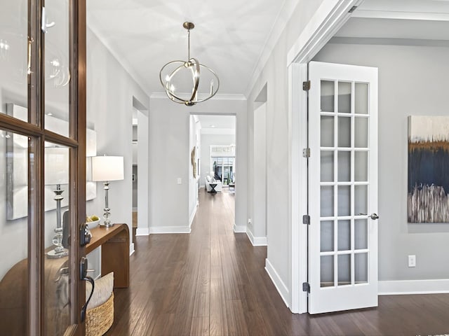 foyer with dark wood-style floors, baseboards, a notable chandelier, and ornamental molding