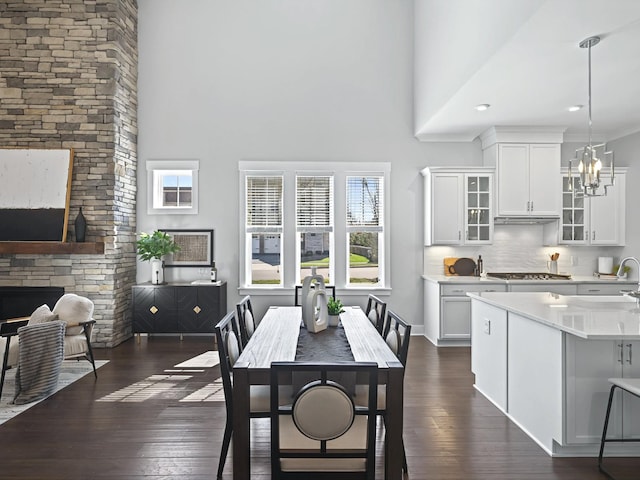 dining room with dark wood finished floors, a chandelier, baseboards, and a towering ceiling