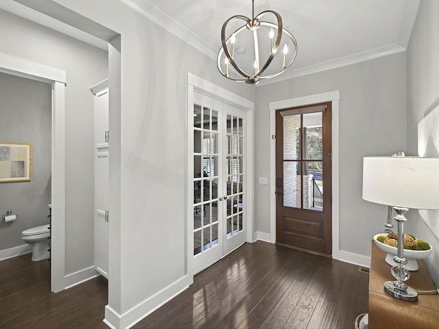 foyer entrance featuring baseboards, an inviting chandelier, crown molding, and hardwood / wood-style flooring