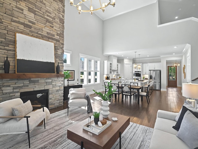 living room featuring wood finished floors, baseboards, a fireplace, crown molding, and a notable chandelier