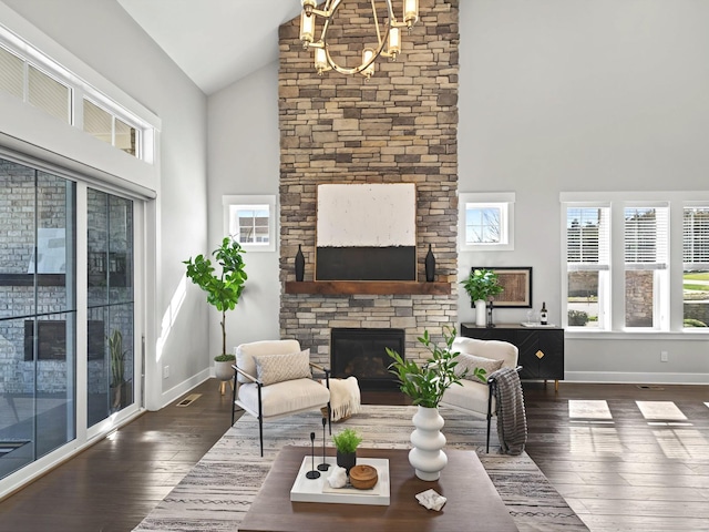 living room with dark wood-type flooring, baseboards, a stone fireplace, an inviting chandelier, and high vaulted ceiling