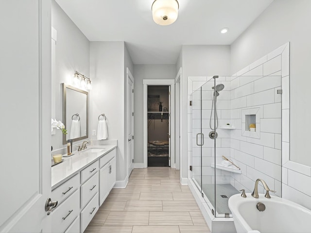 bathroom featuring vanity, baseboards, a soaking tub, a shower stall, and a spacious closet