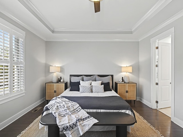 bedroom with a tray ceiling, multiple windows, and dark wood finished floors