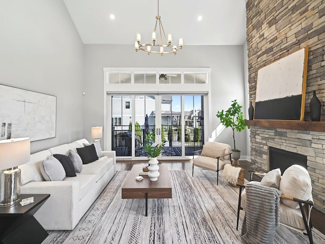 living room featuring a notable chandelier, high vaulted ceiling, wood finished floors, french doors, and a stone fireplace