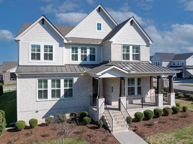 craftsman-style home featuring metal roof, brick siding, a porch, and a standing seam roof