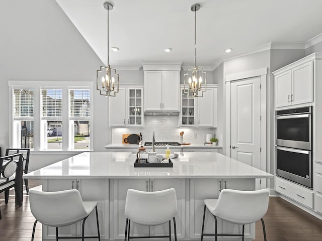 kitchen featuring stainless steel double oven, light countertops, a kitchen bar, and an inviting chandelier