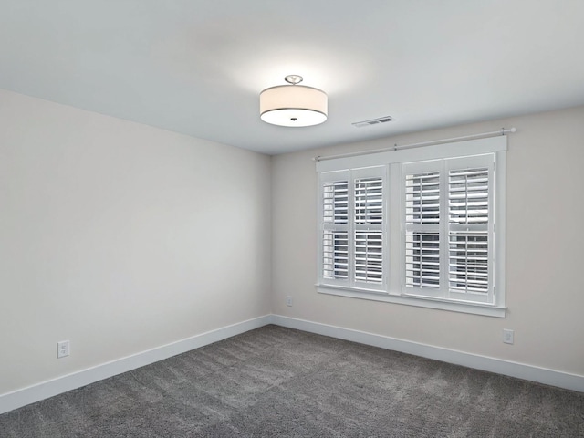 unfurnished room with dark colored carpet, visible vents, and baseboards