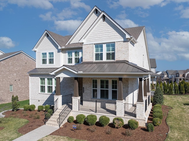 craftsman-style house featuring a standing seam roof, brick siding, and covered porch