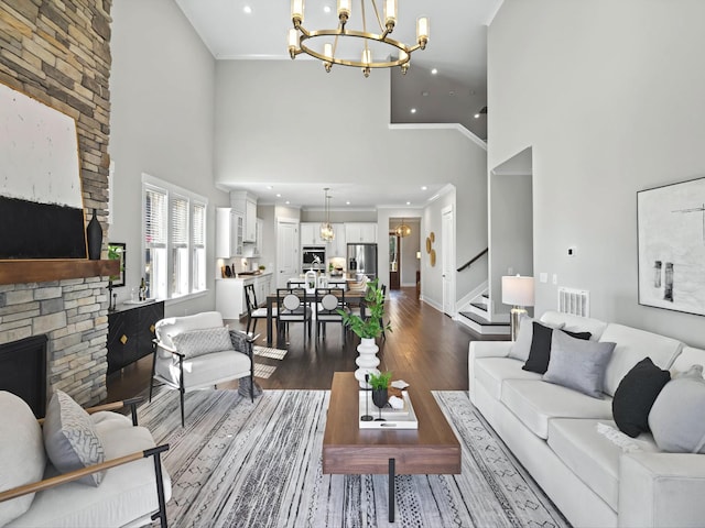 living room featuring visible vents, an inviting chandelier, a fireplace, dark wood-style flooring, and ornamental molding