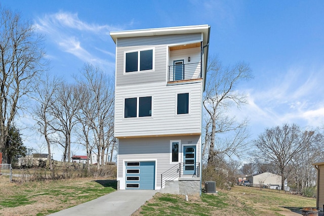 contemporary house featuring a front lawn, a balcony, an attached garage, and central AC unit