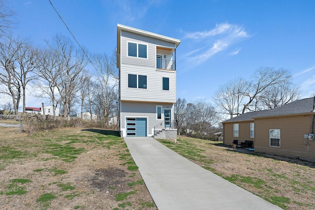 view of front of house with a balcony, fence, a garage, and driveway