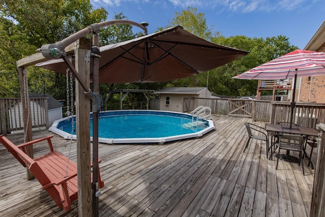 outdoor pool featuring a deck, a storage shed, and an outdoor structure