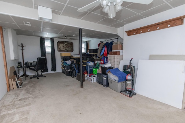 below grade area with carpet flooring, visible vents, a paneled ceiling, and ceiling fan