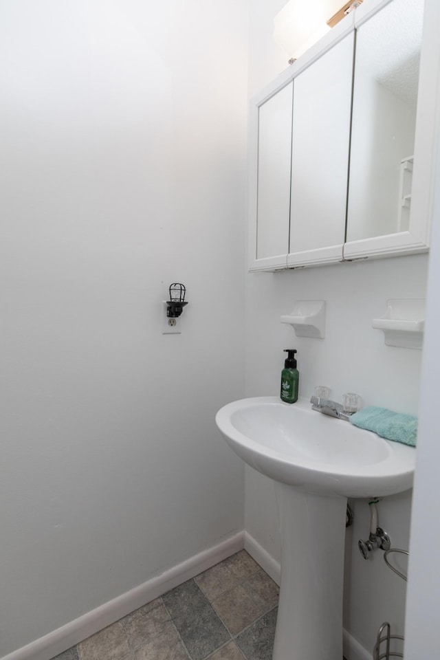 bathroom featuring stone finish floor and baseboards