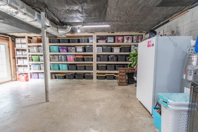 below grade area featuring concrete block wall and freestanding refrigerator