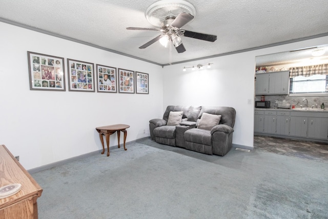 living room with a ceiling fan, baseboards, dark carpet, and a textured ceiling