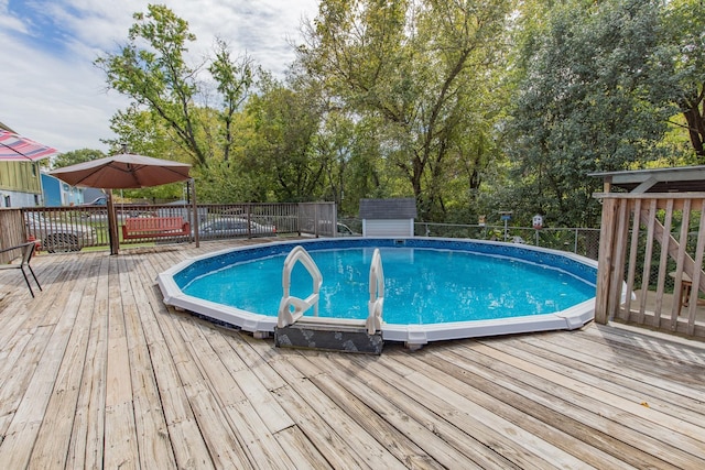 view of swimming pool with a storage unit, a fenced in pool, an outdoor structure, and a deck