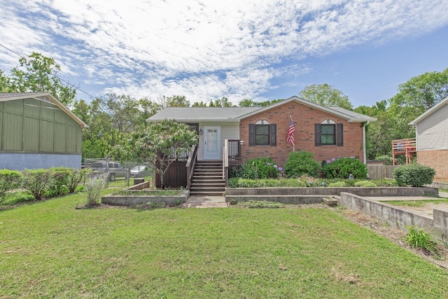 view of front of home featuring brick siding, stairway, a front yard, and fence