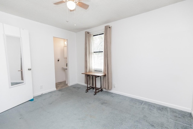 carpeted spare room featuring ceiling fan, baseboards, and a textured ceiling