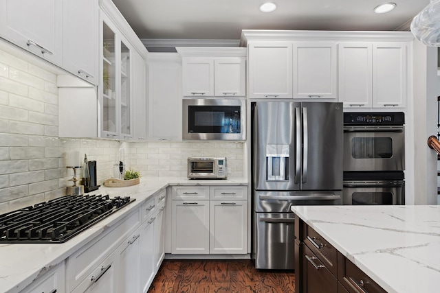 kitchen featuring white cabinetry, glass insert cabinets, tasteful backsplash, and stainless steel appliances