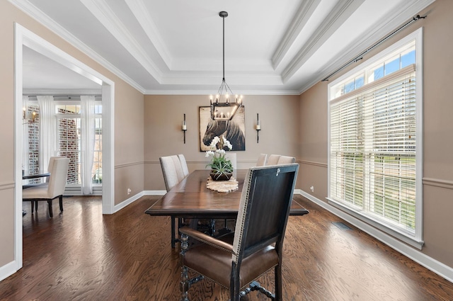 dining room featuring crown molding, baseboards, dark wood-type flooring, a tray ceiling, and an inviting chandelier