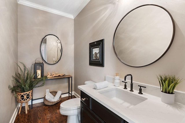 half bath featuring toilet, wood finished floors, crown molding, baseboards, and vanity