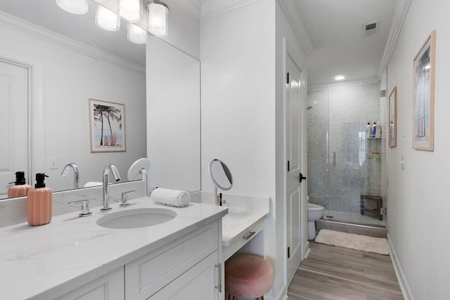 bathroom with visible vents, crown molding, a stall shower, wood finished floors, and vanity