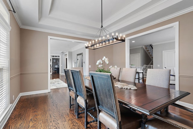 dining area featuring ornamental molding, wood finished floors, stairway, baseboards, and a raised ceiling