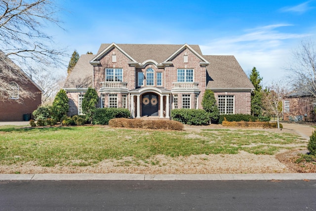 view of front of property with brick siding, a shingled roof, and a front yard