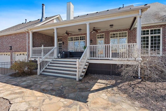 exterior space featuring covered porch, a ceiling fan, brick siding, and a chimney