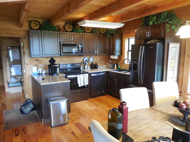 kitchen with beamed ceiling, a sink, stainless steel appliances, light wood-style floors, and wooden ceiling