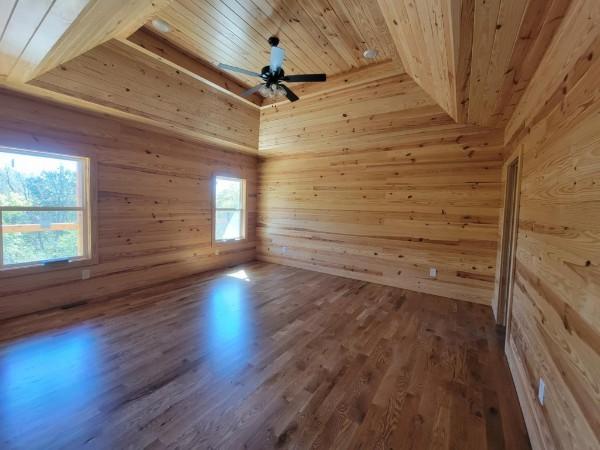 spare room featuring dark wood-style floors, wooden walls, wood ceiling, and a ceiling fan