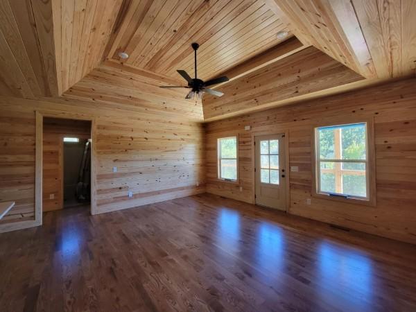 empty room featuring wooden walls, wooden ceiling, and wood finished floors