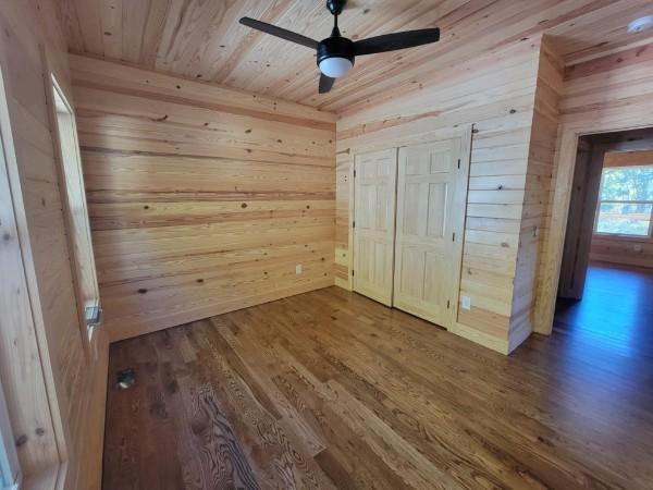 unfurnished bedroom featuring a closet, wood finished floors, wooden walls, and wooden ceiling