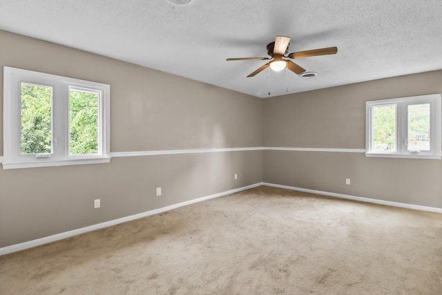 carpeted spare room featuring ceiling fan, baseboards, visible vents, and a textured ceiling