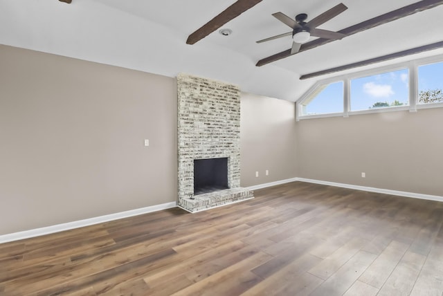 unfurnished living room with wood finished floors, baseboards, a brick fireplace, ceiling fan, and vaulted ceiling with beams