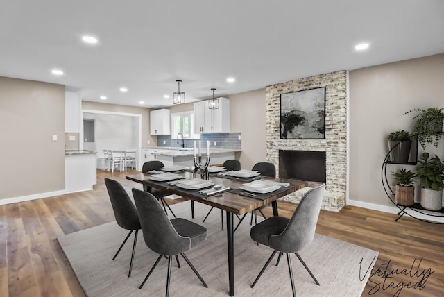 dining room with a fireplace, recessed lighting, light wood-style floors, and baseboards