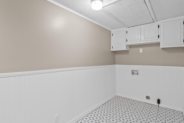 washroom with a wainscoted wall, washer hookup, a textured ceiling, cabinet space, and light floors