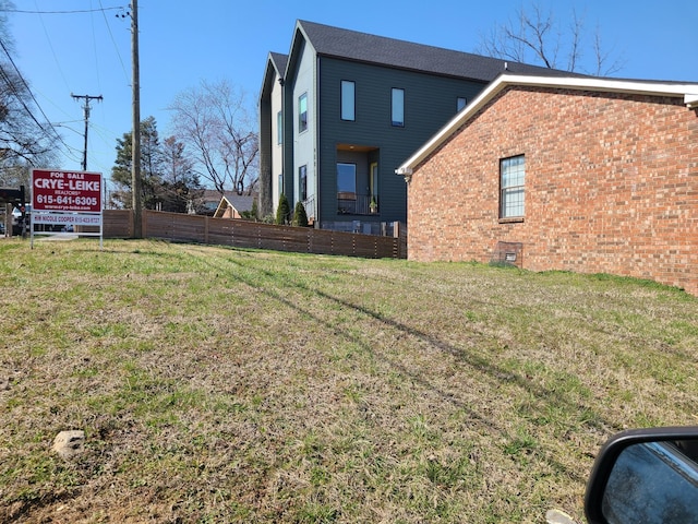 exterior space featuring a yard, fence, and brick siding